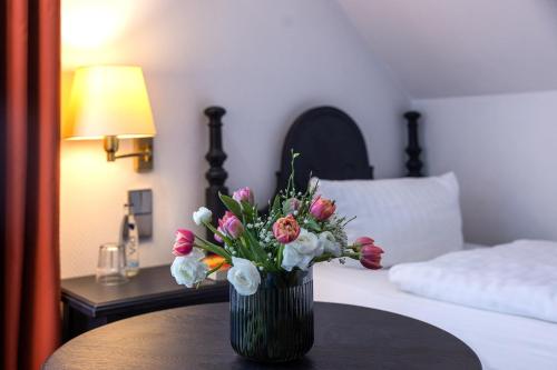 a vase of flowers sitting on a table in a bedroom at Hotel Stadt Gütersloh in Gütersloh