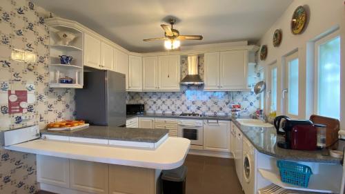 a kitchen with white cabinets and a ceiling fan at Casa do Miradouro in Carrapateira