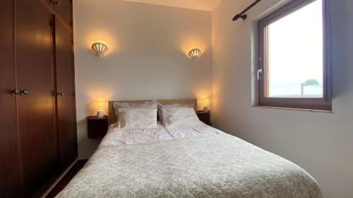 een slaapkamer met een bed met witte lakens en een raam bij Casa do Miradouro in Carrapateira