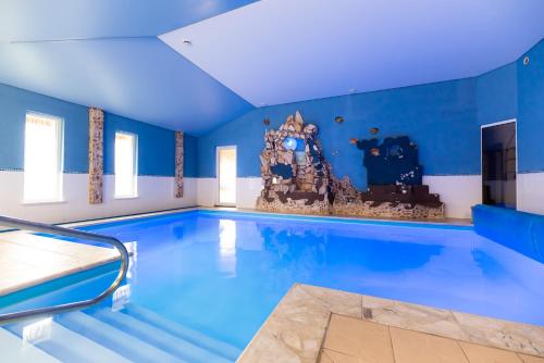 a large indoor swimming pool with a blue ceiling at Leśna Oaza in Borek