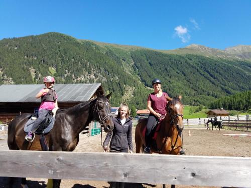 three women are riding horses with a woman at Alpin Appart Reiterhof in Niederthai