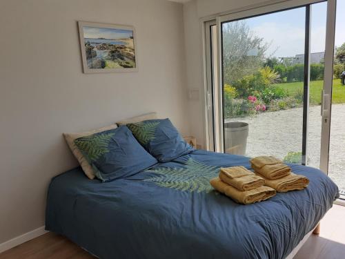 una camera da letto con un letto con lenzuola blu e una finestra di Chambre d'hôte Milin An Awel a Pleumeur-Bodou