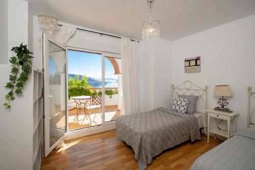 a white bedroom with a bed and a balcony at Lovely villa with jacuzzi and heated pool in Almuñécar