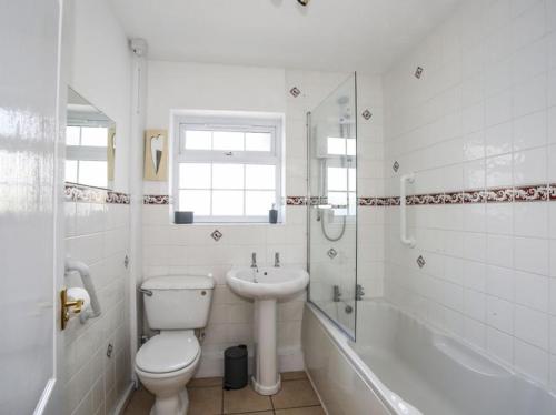 a white bathroom with a toilet and a sink at Homely 4-Bed House close to stunning beach in Pwllheli