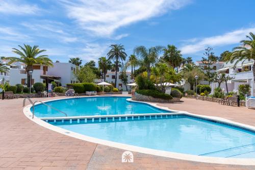 una piscina en un complejo con palmeras en Mediterranean Way - Punta Prima, en La Pineda