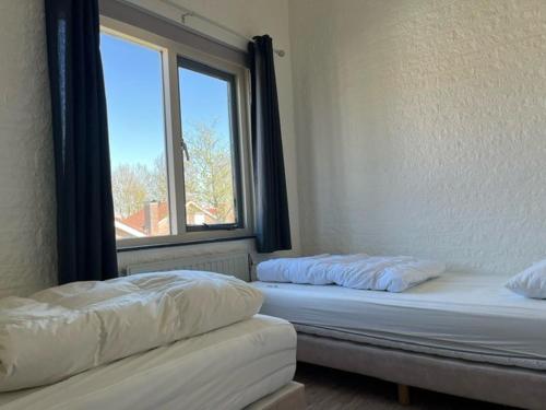 two beds in a room with a window at Kustverhuur, Park Schoneveld, Strandparel 357 in Breskens