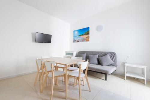 un soggiorno con tavolo, sedie e divano di Mare del Salento Residence by BarbarHouse a Torre Lapillo