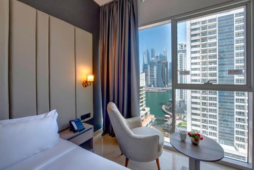 a hotel room with a bed and a table and a large window at Royal Regency Suites Marina in Dubai