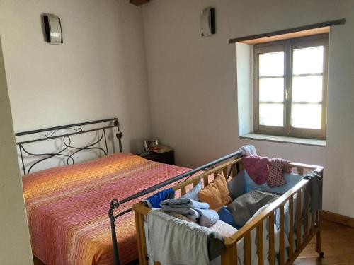 Una cuna en un dormitorio con ventana en Casa in sasso con piscina, en Vernasca