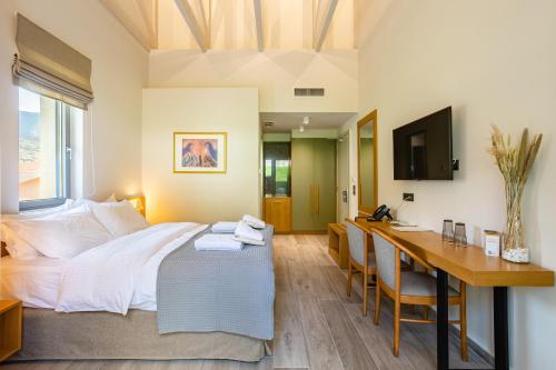 a bedroom with a bed and a desk with a computer at Denthis Hotel - Taygetos Mountain Getaway in Artemisía