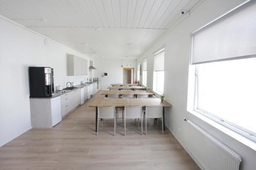 a room with tables and a kitchen with white cabinets at Eiðar - Hostel in Eiðar