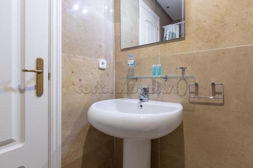 ein Badezimmer mit einem weißen Waschbecken und einem Spiegel in der Unterkunft marina duquesa 839 in Manilva