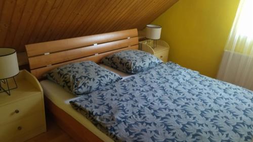 a bed with a blue comforter and two pillows at Dovolenkovy dom in Ružomberok