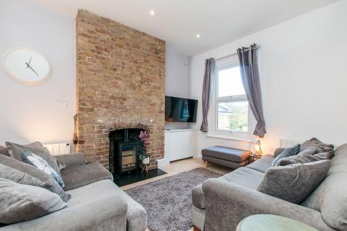 a living room with two couches and a brick wall at Lighthouse View - Apartment by the Sea in Margate
