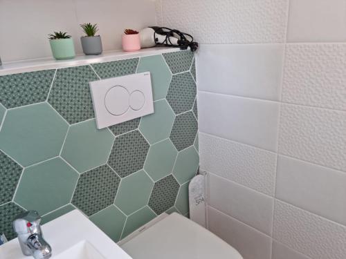 a bathroom with green and white tiles and a toilet at Le Secret de Sanary in Sanary-sur-Mer