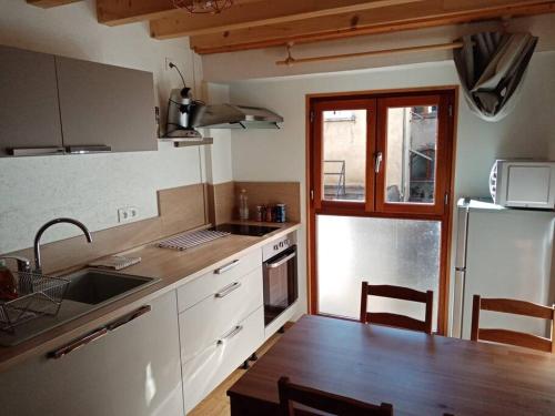 a kitchen with a sink and a table and a refrigerator at Maison de ville 4pers in Issoire