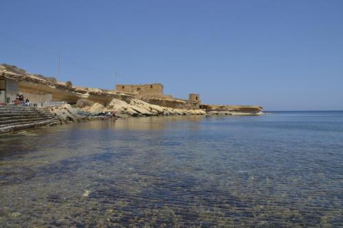 a large body of water with a castle in the background at Horizon Apartments Gozo in Marsalforn