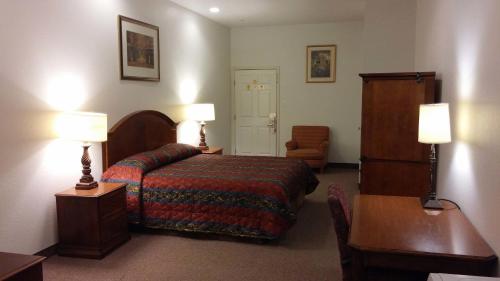 a hotel room with a bed and a table and two lamps at Country Regency Inn & Suites in Manvel