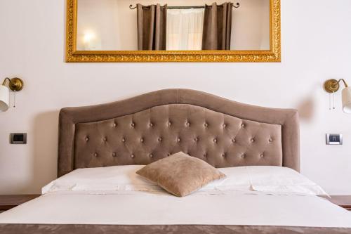 una cama con un espejo enmarcado en oro sobre ella en B&B Chez Moi, en Bolonia