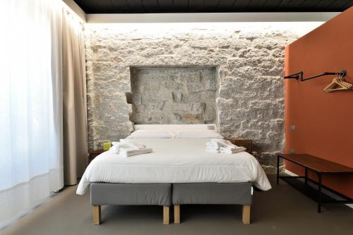 a bedroom with a bed and a brick wall at Loft Favoloso con piscina in Tortolì
