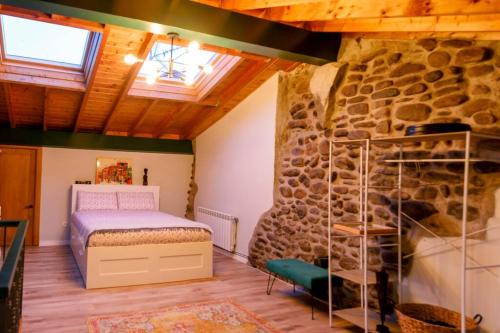 1 dormitorio con cama y pared de piedra en Casa el Envero en Saro