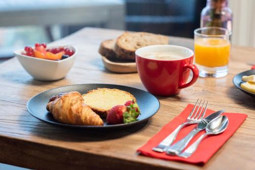 een tafel met een bord ontbijtproducten en een kopje koffie bij Alba hotel in Saint-Malo