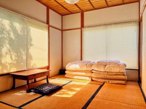 a room with a bed and a table and windows at Sai Holiday House Ohama Beach - Max 9 ppl in Shimoda