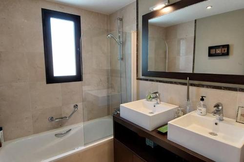 La salle de bains est pourvue de 2 lavabos, d'une baignoire et d'un miroir. dans l'établissement Chic Beachfront Apartment, à Torrox Costa