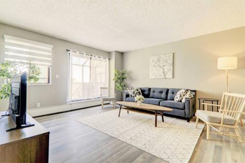 a living room with a couch and a tv at Roomy Top Floor at Stampede w Free Parking and AC in Calgary