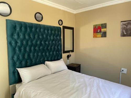 a bedroom with a large bed with a green headboard at Yello guest house in Vanderbijlpark