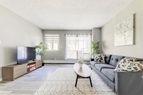 a living room with a couch and a tv at Roomy Top Floor at Stampede w Free Parking and AC in Calgary