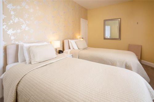 Habitación de hotel con 2 camas y espejo en Hillcrest Bed & Breakfast, en Eyemouth