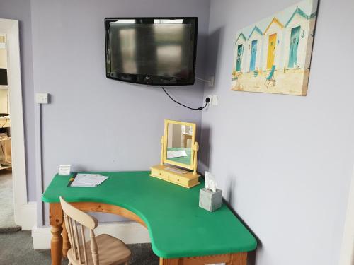 Elle comprend un bureau vert avec un miroir et une télévision murale. dans l'établissement Henrys on the Prom, à Great Yarmouth