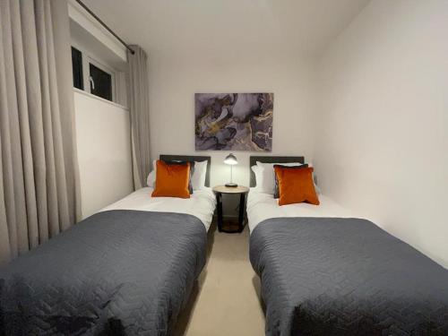 Duas camas individuais num quarto com um candeeiro. em 1-Bedroom Apartments in the Heart of Central Woking em Woking