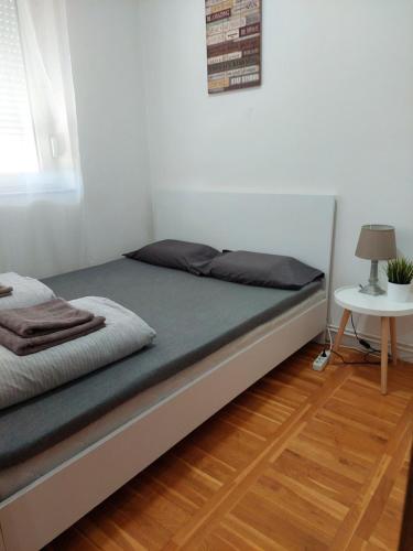 a bed in a white room with a table at Smiley 2 - Subotica Centar in Subotica