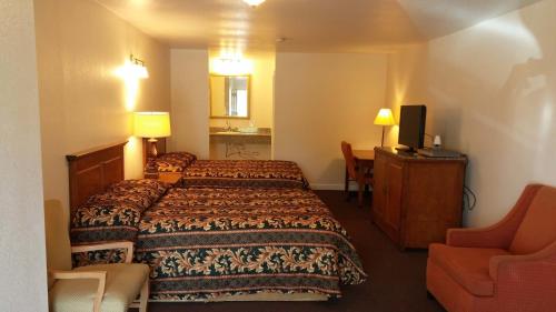 a hotel room with a bed and a chair at Country Regency Inn & Suites in Manvel
