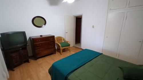 1 dormitorio con 1 cama, TV y vestidor en DEPARTAMENTO DIARIO PASEO DEL JOCKEY, en Córdoba