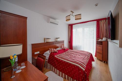 a bedroom with a bed and a table and a window at Aquapark Health Resort & Medical SPA Panorama Morska All Inclusive in Jarosławiec