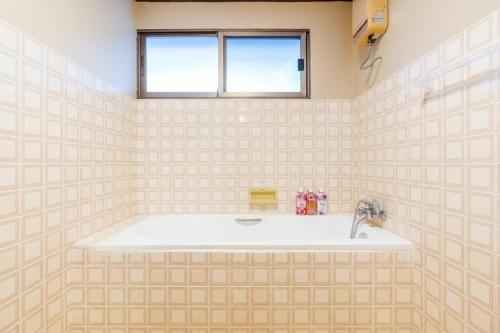 uma banheira numa casa de banho em azulejo com uma janela em City white beach house2 Hua Hin em Hua Hin