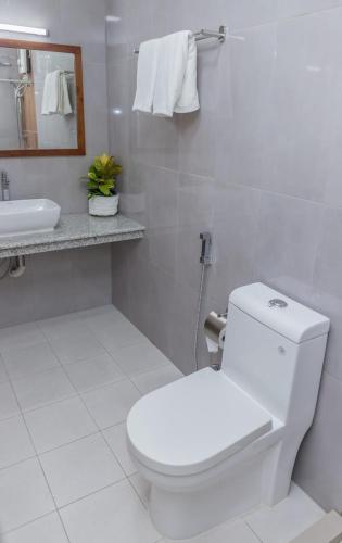 a white bathroom with a toilet and a sink at Nihaali Maldives in Kudarikilu