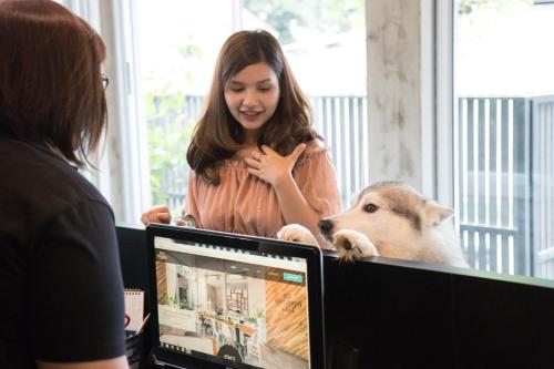 a woman standing in front of a computer with a dog at Ketawa Pet Friendly Hotel in Chiang Mai