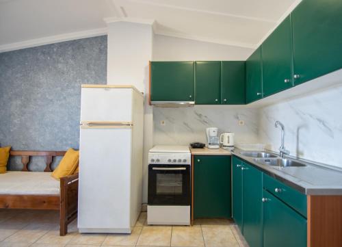 a kitchen with green cabinets and a white refrigerator at Salt Lake junior Suites in Alykes