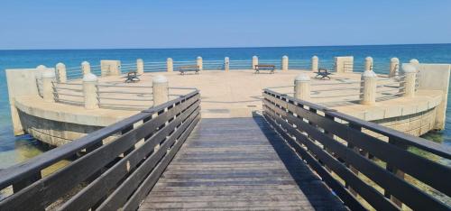 a wooden pier with benches on the beach at Da DOMITILLA in centro storico con panorama in Avola