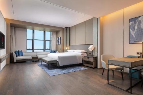 佛山市にあるFoshan Marriott Hotelのベッドとデスクが備わるホテルルームです。