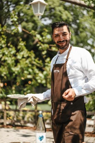 a man in an apron holding a plate of food at La Cantinota - Locanda De Manincor Rooms in Arco