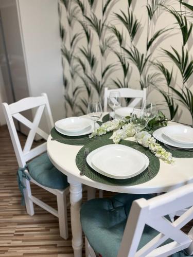 a white dining room table with white plates and chairs at Apartament na Starówce Boho in Pszczyna