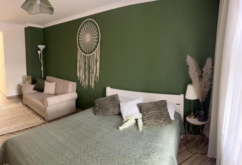 a green bedroom with a bed and a chair at Apartament na Starówce Boho in Pszczyna