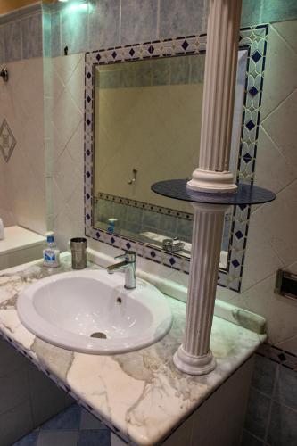 a bathroom sink with a column and a mirror at Casa Vacanze "A Machina Ro Ghiaccio" in Noto