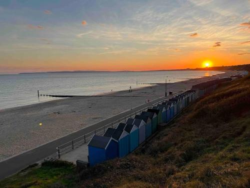 a beach with a row of beachbreaks at sunset at The Retreat - Luxury apartment, 2 mins from beach. in Bournemouth