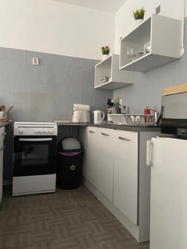 una cocina con armarios blancos y horno negro en Studio indépendant dans maison de ville, au calme, en Marsella